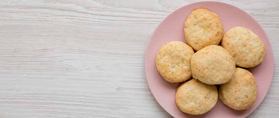 Homemade Flaky Buttermilk Biscuits on a pink plate on a white wooden surface, top view. Flat lay, overhead, from above. Copy space.