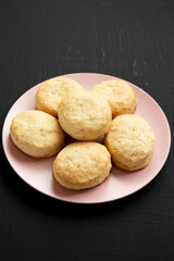Homemade Flaky Buttermilk Biscuits on a pink plate on a black background, low angle view.
