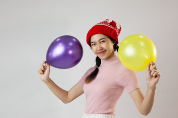 Portrait of cute asia woman wearing a red wool hat. Holding a balloon and smiling. On white background