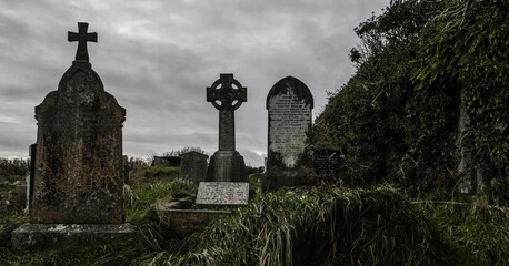 Fototapeta na wymiar Ireland celtic cross at medieval church cemetery Old spooky cemetery . Haunted cemetery. Scary place. Old graves 