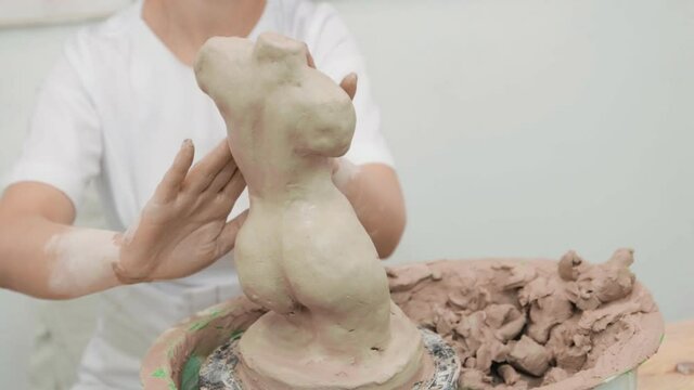 Girl sculptor artist creating a bust sculpture with clay. Sculptor at work. Close up