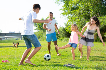Group of smiling children and parents having fun together outdoors playing football. High quality photo