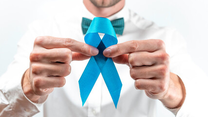 Cancer people. Hipster men in bright shirt, cyan bowtie with blue ribbon in hands on white background. Awareness prostate cancer of men health. Man Healthcare and World cancer day concept.