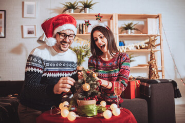 Happy couple decorating Christmas tree in their home