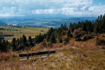 autumn wooden bench and panoramic view of Pieniny Mountains and Czorsztynskie Lake seen from Wdzar mountain in Kluszkowce in Poland