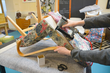 Making new upholstery on old chair. Woman hands working in upholstery workshop with pneumatic...