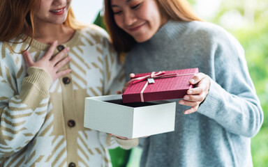 Surprised young women opening a gift box together