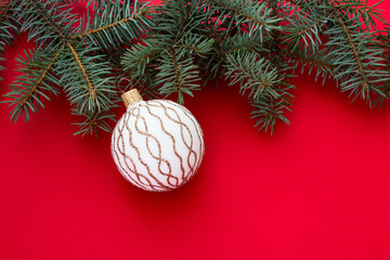Christmas decorations. Fir branches and Christmas ball against red background with place for text. Christmas and New Year. Blank for congratulations. Flat layout.