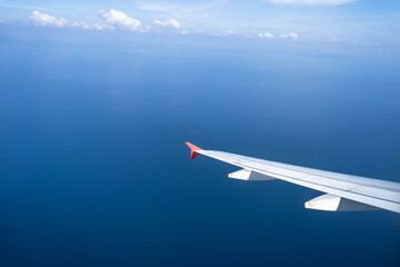 Fototapeta na wymiar Airplane wing against beautiful blue ocean.