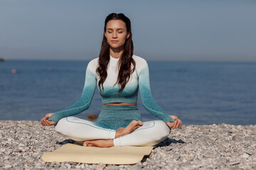 Naklejka na ściany i meble Caucasian young woman practicing yoga at seashore