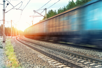 Motion blurred heavy cargo freight rusty train wagons moving on railway on sunset or sunrise day...