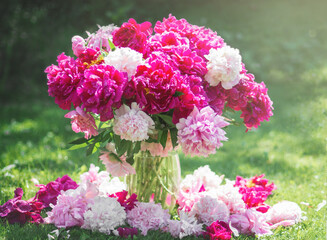 Obraz premium bouquet of fresh, lush, fragrant multi-colored peonies in a stylish glass vase and a white porcelain Cup near a window wet From raindrops, a cozy home decoration, Breakfast at home in bad weather