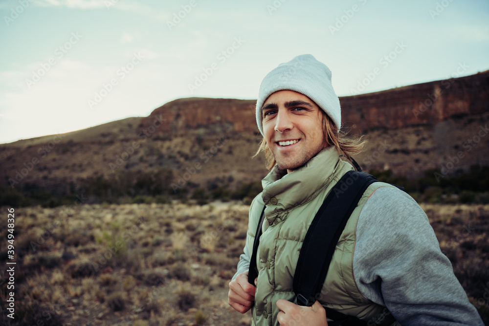 Wall mural portrait of smiling caucasian male teenager enjoying hike in mountain spending alone time