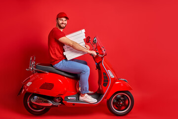Fototapeta na wymiar nice caucasian male guy driving moped motorcycle bringing pile stack pizza order, delivery male is in a hurry to deliver orders isolated over red color background
