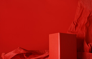 Empty red rectangular podium on red background with crumpled paper