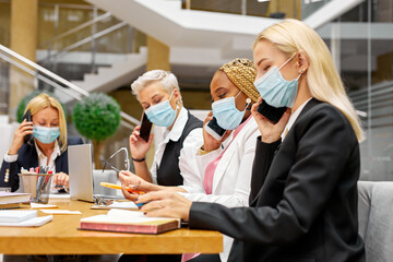 side view on people in masks in the office during work. covid-19 pandemic concept