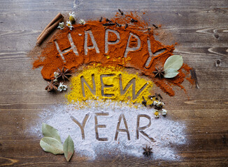 Happy New Year 2021 written on cinnamon, spices, paprika,salt on a wooden background. Christmas...
