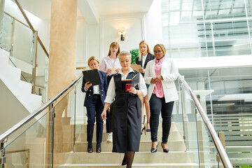 team of co-workers going down the stairs after meeting, discussing business project, in formal clothes