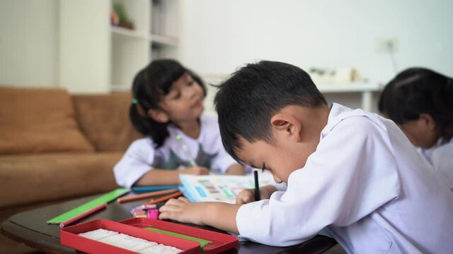 Asian student is writing on the book in the classroom at school.