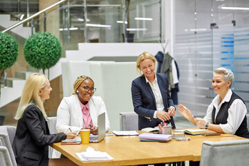 team of friendly business women talking while sitting at table, use laptop. international cooperation, discussing startups