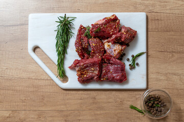 raw lamb chops with rosemary and pepper on marble board. preparing meat. marinated meat. beef. preparing food on kitchen. cooking. beef steak with vegetables