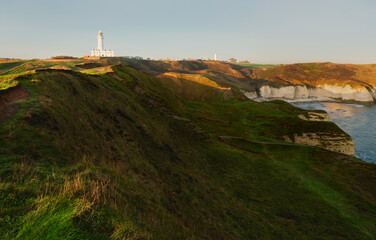 Fototapeta na wymiar View across English coastline towards lighthouse at sunrise. Flamborough, UK.