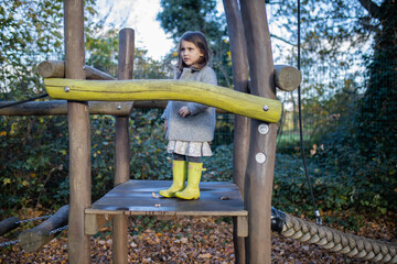 Obraz premium Little girl standing in wooden playground at a park