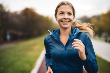 Fototapeta Beautiful adult woman is jogging outdoor on cloudy day in autumn. obraz