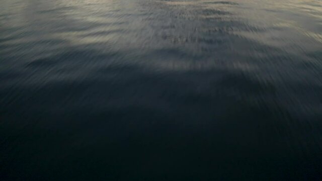 Aerial drone jurassic park opening style shot flying low over water, slowly tilting up to reveal colourful sunset sky to the horizon