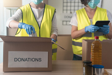 Volunteer teamwork in charitable foundation wearing face masks - Food donations concept