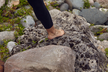  A woman walks on stones barefoot. bare female feet close-up.