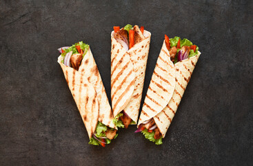 Mexican tortilla grilled wrap with chicken breast and vegetables on concrete background