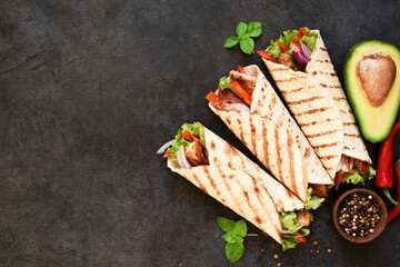 Mexican tortilla grilled wrap with chicken breast and vegetables on concrete background