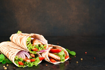 Mexican tortilla grilled wrap with chicken breast and vegetables on concrete background