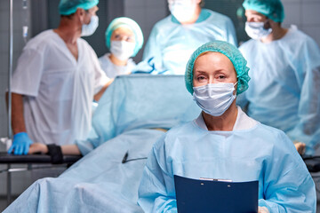 portrait of assistant of doctors, woman in mask and uniform hold digital tablet of patient's...