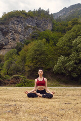 Naklejka na ściany i meble Yoga classes in nature. The concept of playing sports alone. Social exclusion. A woman does yoga in the mountains