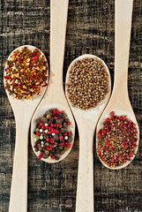 A mixture of various spices in a wooden spoon. Spices and seasonings on an old shabby board. Mix on a pile close up.