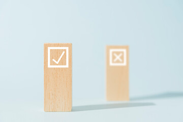 Concepto elección, cubos de madera con símbolos de v y x, marcación de casillas, fondo azul con espacio de copia