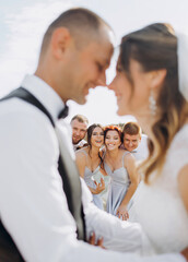 Fototapeta na wymiar Happy newlyweds kiss on the background of friends