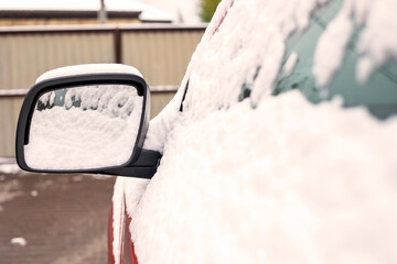 snow-covered left car mirror, natural background, first snow