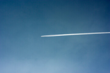 White trail from flying planes on the blue autumn sky.