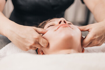Fototapeta na wymiar Technique for performing a facial massage in a beauty salon - hands of a professional masseur - rejuvenation and relaxation of facial muscles