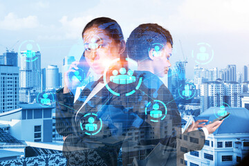 Two young astonishing SMM specialists working on social media marketing strategy to achieve business goals. Hologram icons over Kuala Lumpur background.