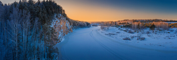 Winter landscape. Sunset over mountain cliff and snowy river panorama.