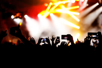 Silhouette of hands using camera phone to take pictures and videos at live concert