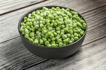Frozen pea in the bowl on gray wooden table. Horizontal orientation. Close-up.