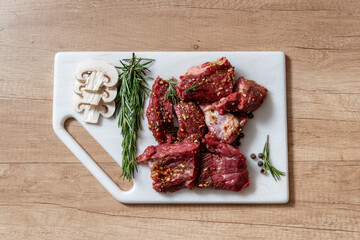 raw lamb chops with rosemary and pepper on marble board. preparing meat. marinated meat. beef. preparing food on kitchen. cooking. beef steak with vegetables