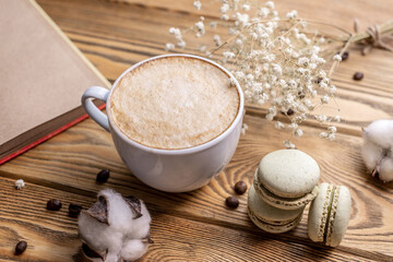 Cup of aromatic coffee, macaroons and a notebook on a wooden table. Concept of a nice coffee break and lifestyle
