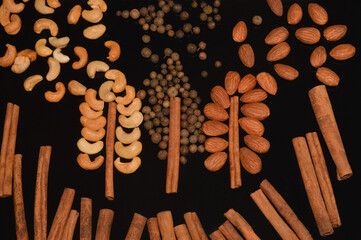 Scattered handfuls of almonds and cashews, allspice and cinnamon. Placers of nuts in the form of trees. Close-up. Top view.