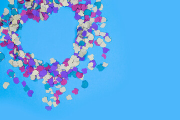 Valentine composition with a heart in confetti on blue background